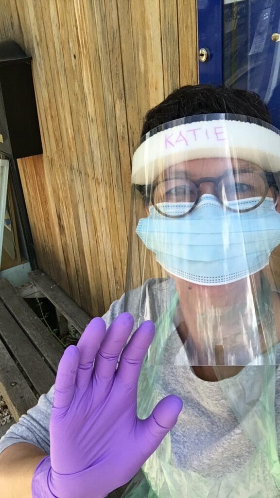 Katie wearing a disposable mask, a visor, and latex gloves, at the Community Food Hub