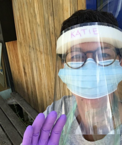 Katie in a mask and visor at the food hub