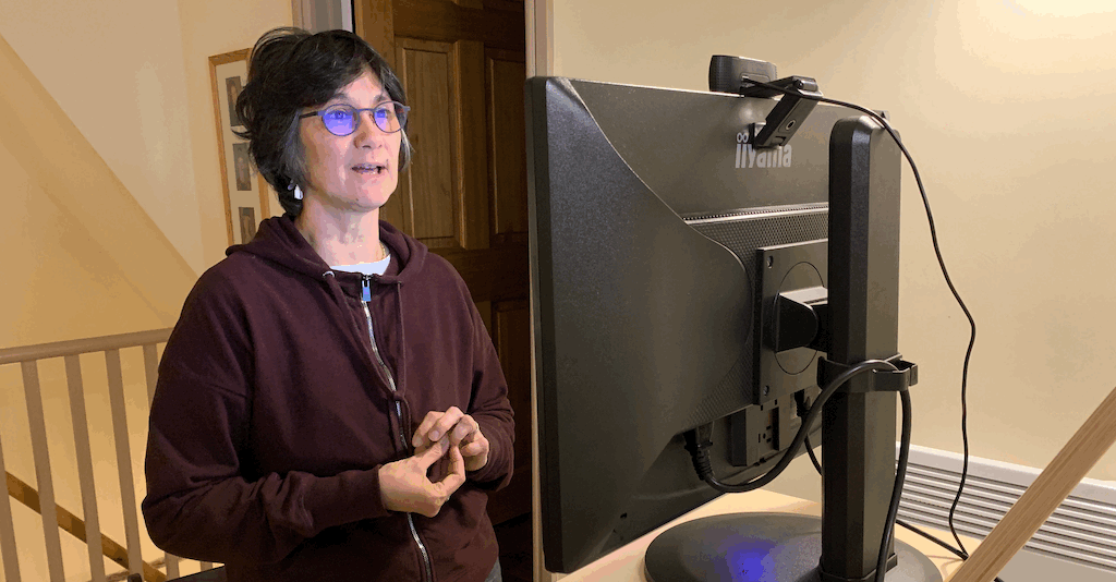 Katie standing looking at a screen. The rear of the monitor is visible