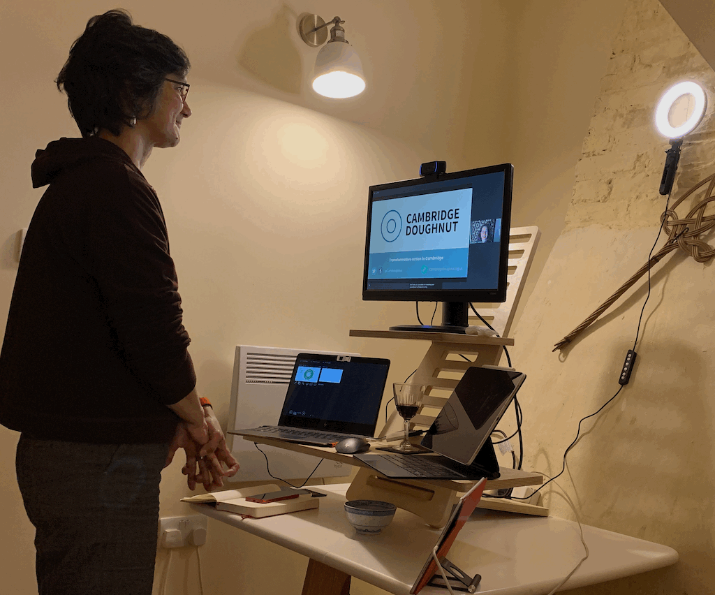 Katie during the session, with a laptop and a second screen, two iPads and a phone, all arranged on a standing desk. A ring light illuminates her