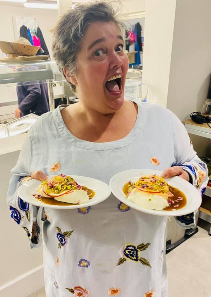 Alex Collis in a kitchen with two plates of delicious food