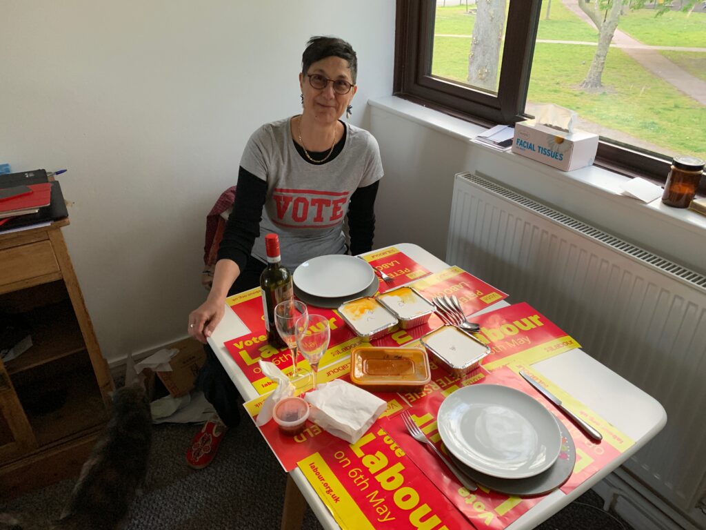 Katie at a table set for a meal, with several Labour posters as table mats