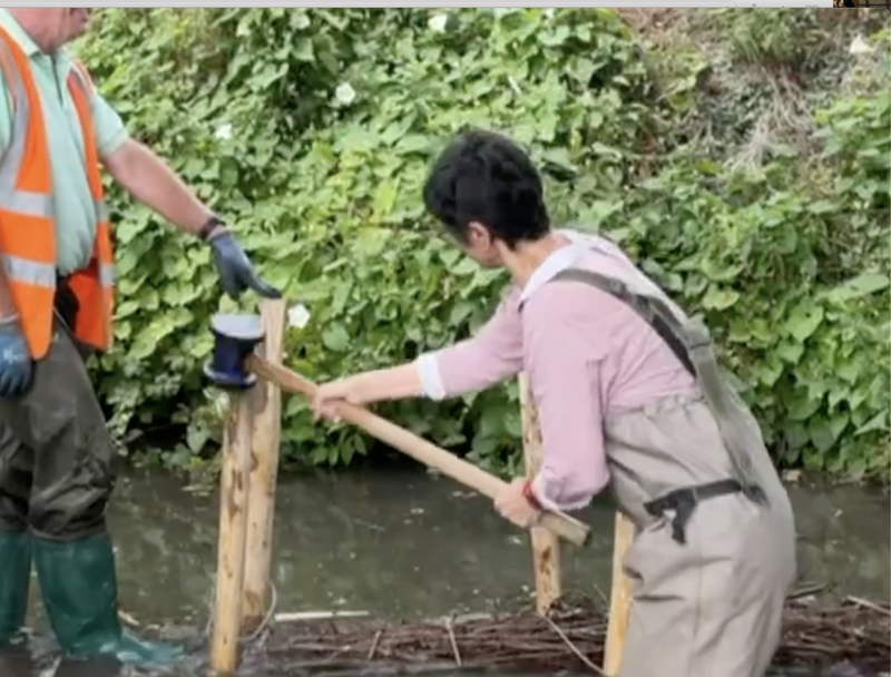 Katie using a sledgehammer to hammer in a post